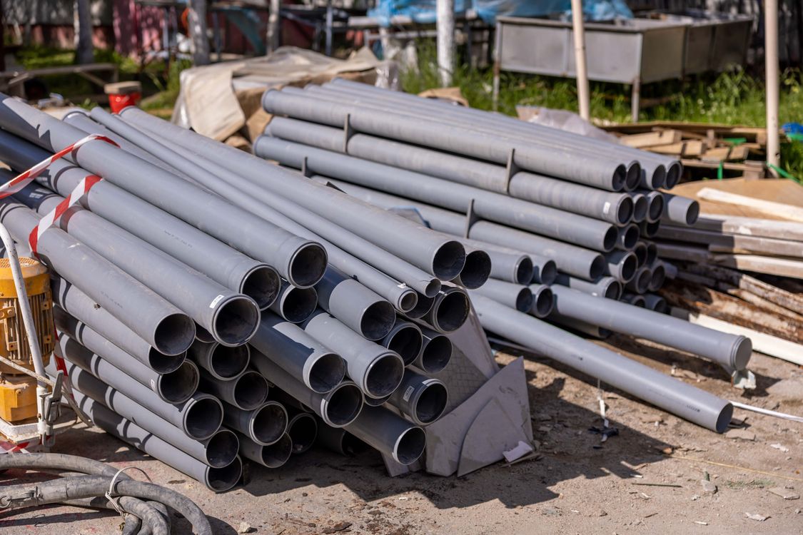 Stacked grey PVC pipes at a building site